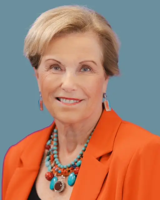 Dr. E. Ann McGee in an orange jacket on a light blue background