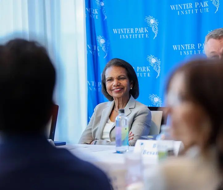 Condoleezza Rice seated with guests in front of a Winter Park Institute backdrop.